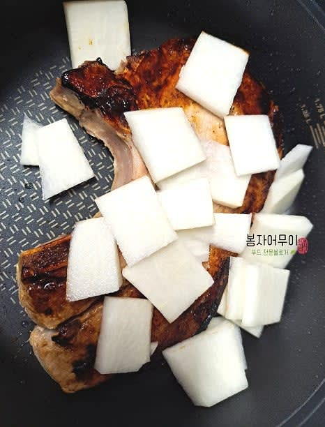 앞뒤가 노릇노릇해지면 무를 올리고 물을 800ml 부어줍니다. 마늘 3개를 다져 넣고 새우젓 반 스푼 먼저 넣어주세요.