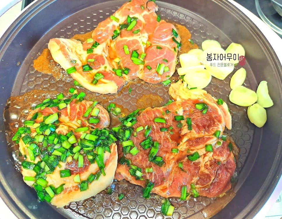 프라이팬을 중불로 달구고, 재운 목살을 넣어 한쪽이 익을 때까지 구워줍니다. 마늘도 같이 굽습니다.