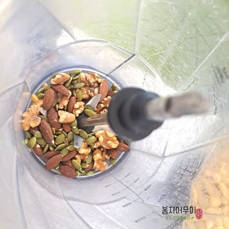 껍질을 벗긴 콩을 믹서기에 넣고 물을 조금씩 부어가며 곱게 갈아줍니다. 견과류와 깨소금을 추가하여 한 번 더 갈아주세요.