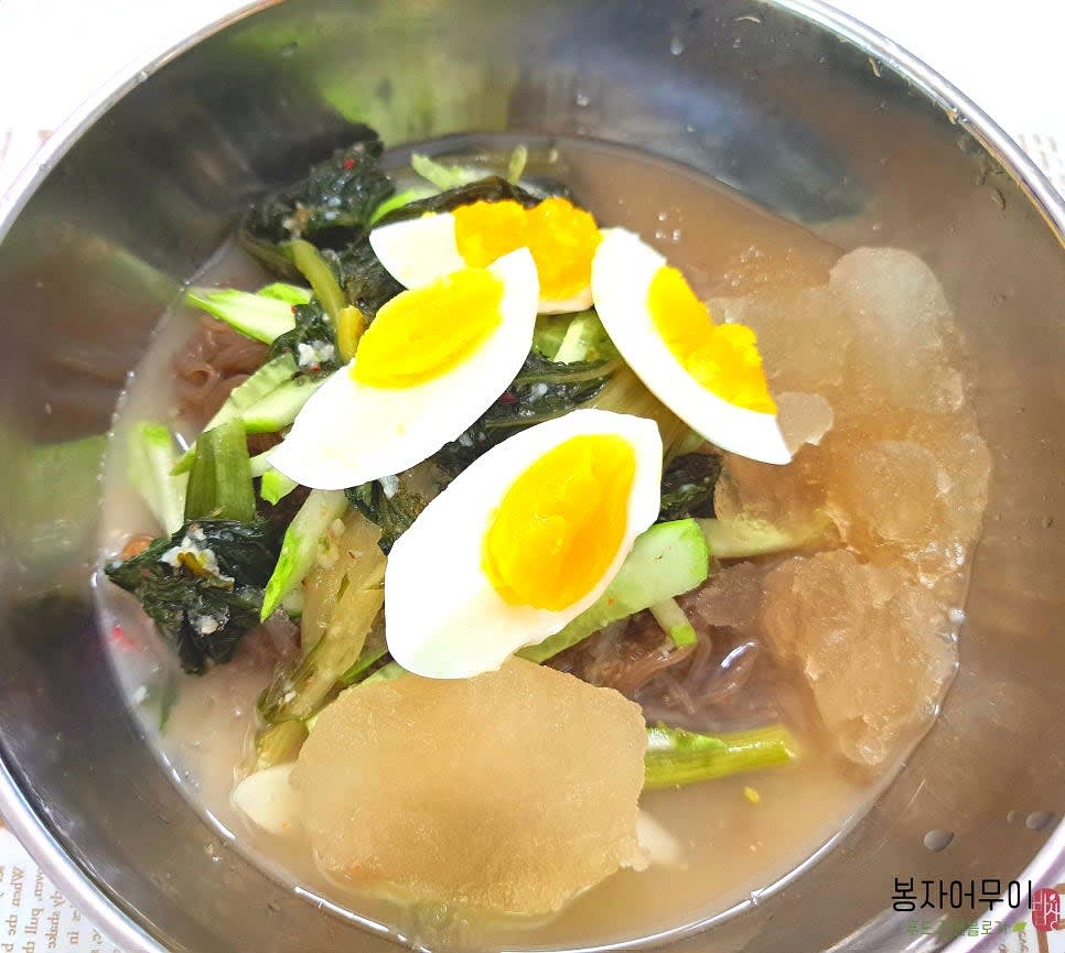 열무 물김치를 그릇에 담고 준비된 냉면을 담습니다. 오이를 얇게 채 썰어 냉면 위에 올리고, 삶아둔 계란도 함께 올립니다.