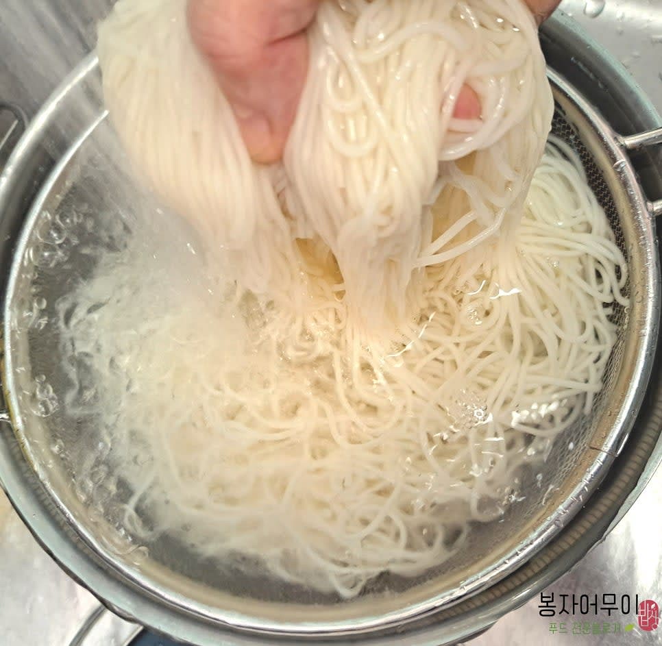 냄비에 물을 끓이고 소금을 약간 넣은 뒤 국수를 삶습니다. 물이 끓어오르면 찬물을 부어 끓이는 과정을 2~3회 반복합니다. 삶은 국수는 찬물에 헹궈 물기를 제거하고 체반에 받쳐줍니다.