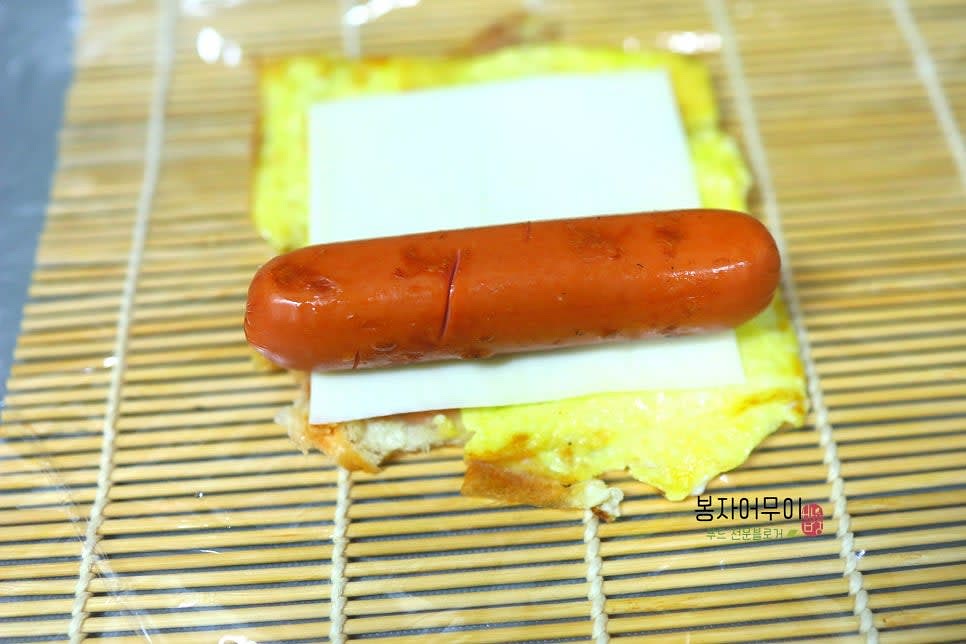 김밥마는 발에 비닐을 깔고 빵 위에 치즈, 치즈 위에 햄을 올리고 꾹꾹 눌러서 돌돌 말아줍니다.