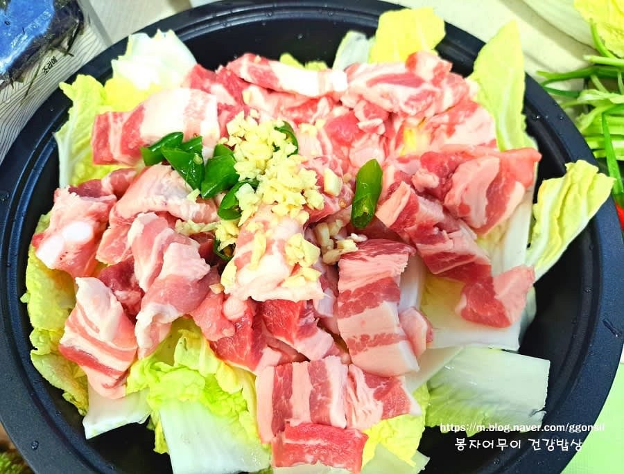 배추 위에 삼겹살을 올리고 그 위에 다진 마늘과 청양고추를 뿌려줍니다.