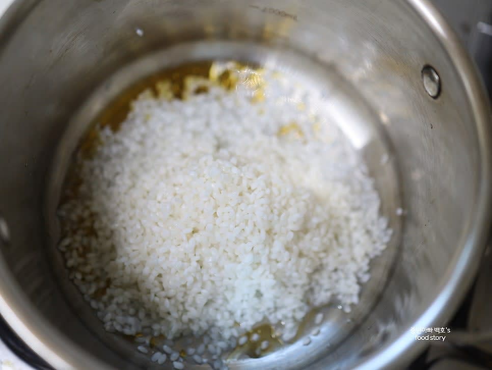 30분간 불려 놓은 쌀을 참기름 1스푼과 함께 볶아 주세요. 눌러 붙는 경우 물을 조금씩 추가해주세요.