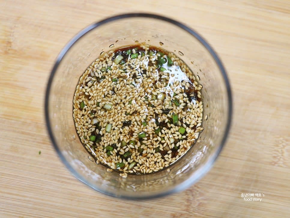 참기름 1스푼과 통깨 1스푼을 섞어 굴밥 양념장을 만듭니다. 다진 마늘 1/2스푼, 양조간장 3스푼, 맛술 1스푼을 넣고 잘 섞어 주세요.