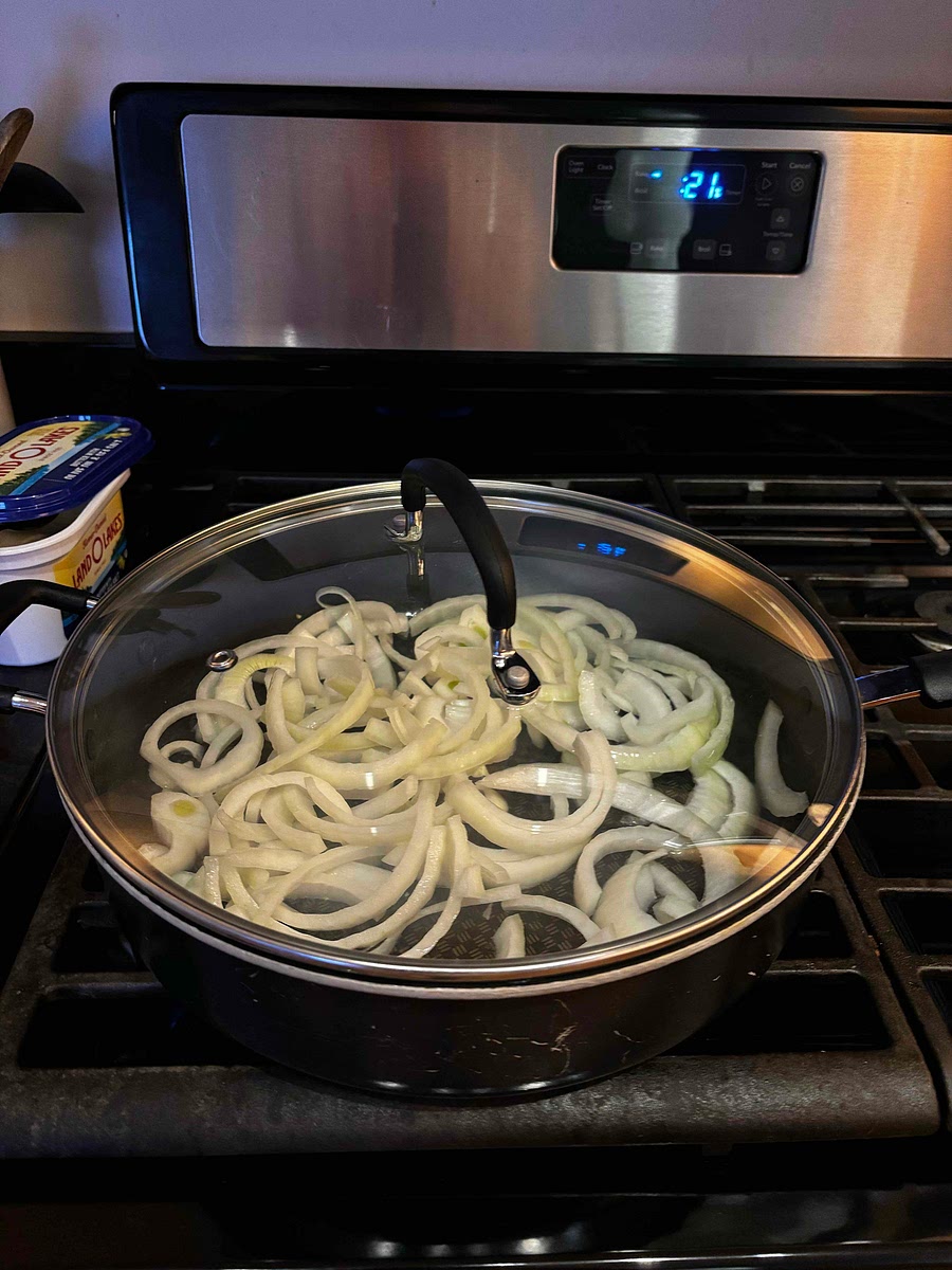 While sausage is cooking, start cutting the onion. Place a small amount of butter into a deep saucepan and coat onions. Cook with lid for about 5 minutes stirring occasionally