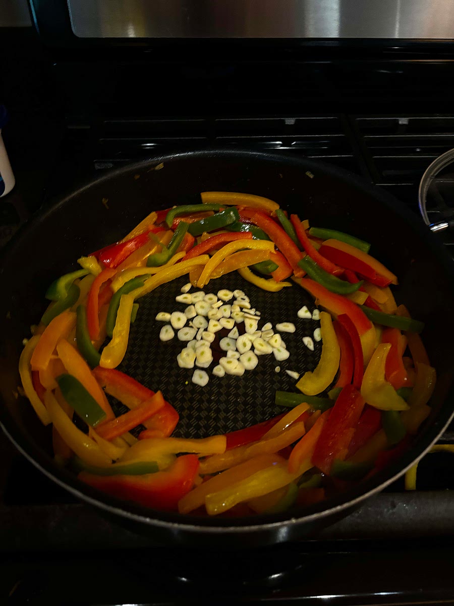 Once peppers are soft, add sliced garlic to middle and cook about 1 minute until fragrant.