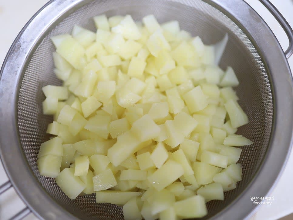 익힌 감자를 채반에 두어 물기를 제거한 뒤, 버터를 추가하여 믹싱 볼에 담아 으깨어 주세요. 알갱이가 약간 남아도 괜찮습니다.