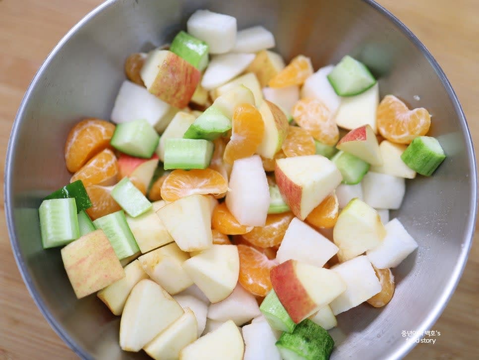 넉넉한 믹싱 볼에 배, 사과, 귤, 오이를 모두 넣습니다.