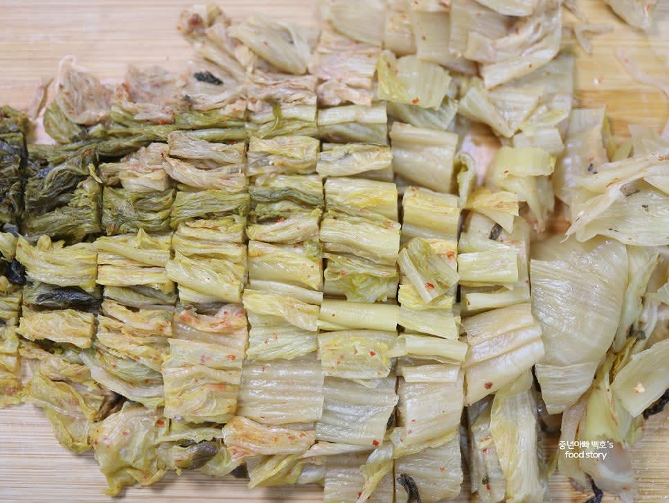 묵은지의 물기를 손으로 짜준 후 길게 놓아주고, 먹기 좋은 크기로 자릅니다. 심지 부분도 얇게 썰어 주세요.