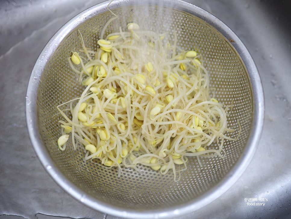 삶은 콩나물을 빠르게 꺼내 흐르는 물에 식힌 뒤 채반에 밭쳐 물기를 완전히 제거합니다.