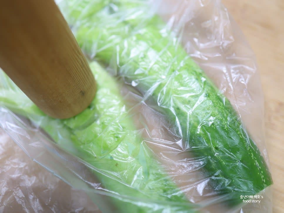 오이를 위생 비닐에 넣고 막대기로 두드리며 손질한 후 손으로 적당한 크기로 잘라 줍니다.