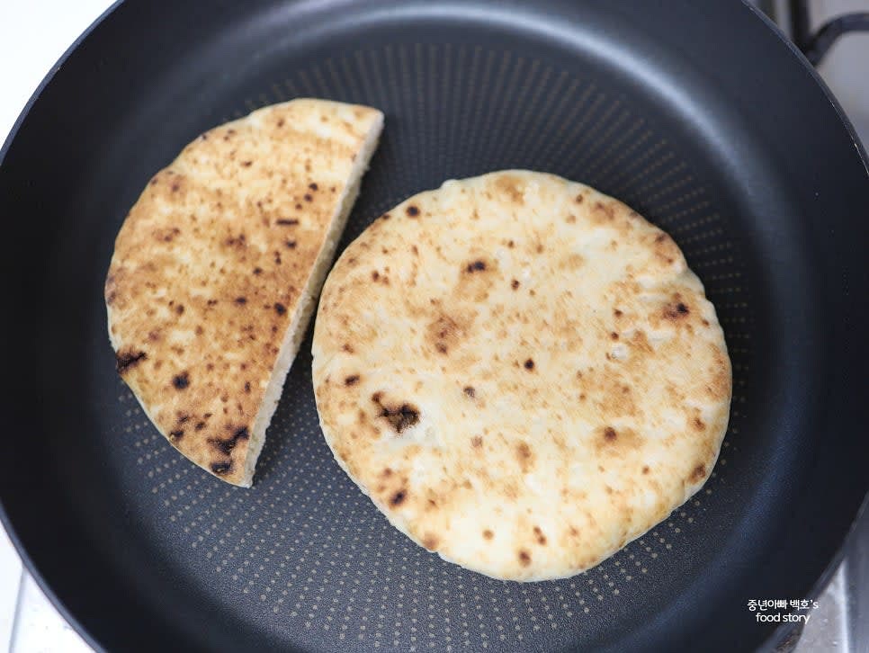 피타 브레드를 약한 불에서 살짝 굽고 반으로 잘라줍니다. 따뜻하고 고소한 맛이 더해집니다.