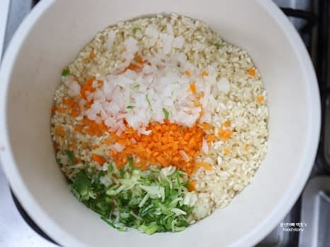 볶아진 쌀에 양파, 당근, 대파를 넣고 함께 볶아 양파가 투명해질 때까지 익혀줍니다.