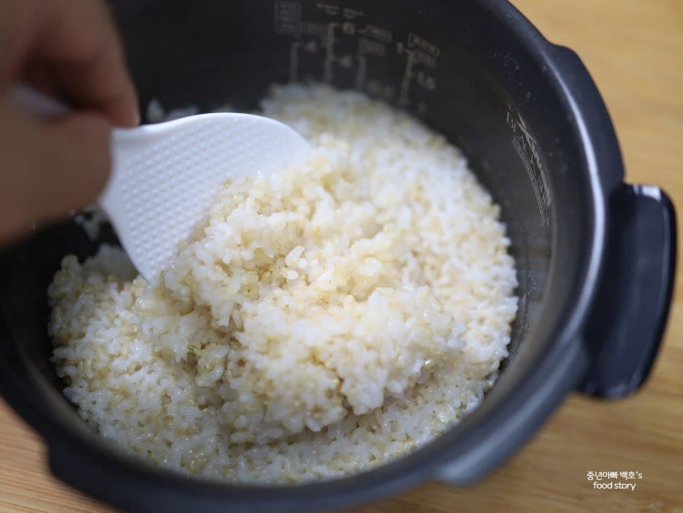 밥이 완성되면 주걱으로 골고루 섞어 공기를 넣어줍니다. 이 과정은 밥을 보슬보슬하게 유지하는 데 중요합니다.