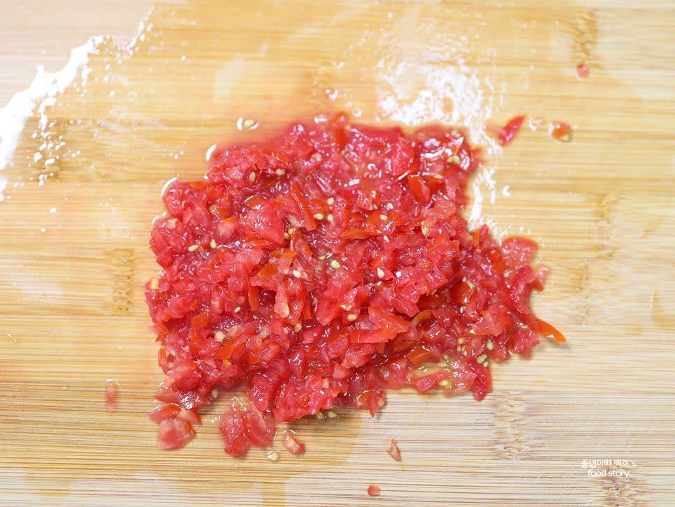 방울토마토를 깨끗이 씻어 잘게 다지고, 양파와 깻잎(또는 고수)을 잘게 다집니다.