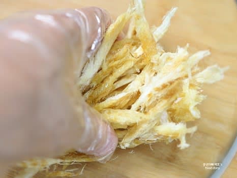 큰 그릇에 황태채를 담고 녹인 버터를 부어 손으로 골고루 버무립니다.