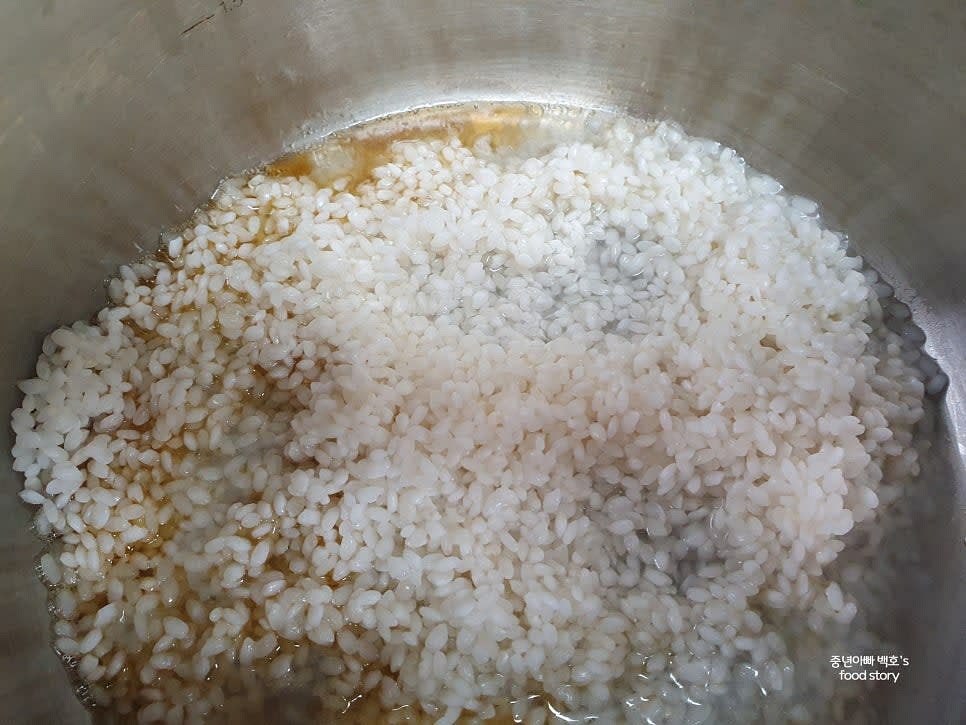 깊은 냄비에 참기름 1스푼을 두르고 약불에서 불린 쌀을 3~4분간 볶아줍니다. 눌어붙으면 물을 약간씩 추가합니다.