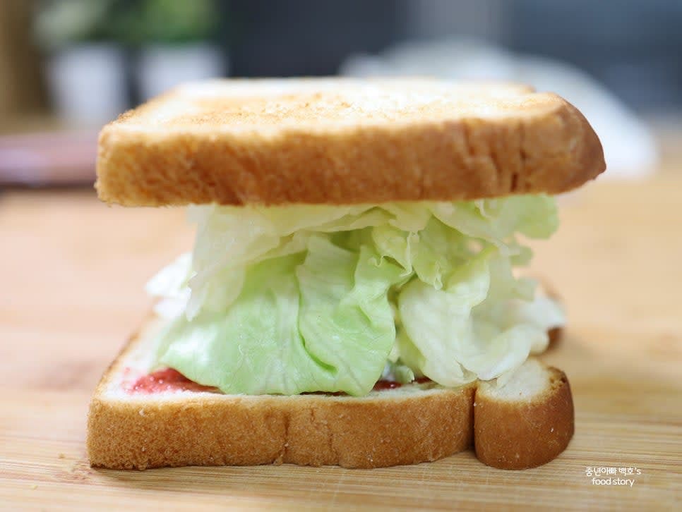 다른 식빵을 위에 덮고, 랩을 사용해 손으로 눌러 흐트러지지 않게 단단히 감쌉니다.