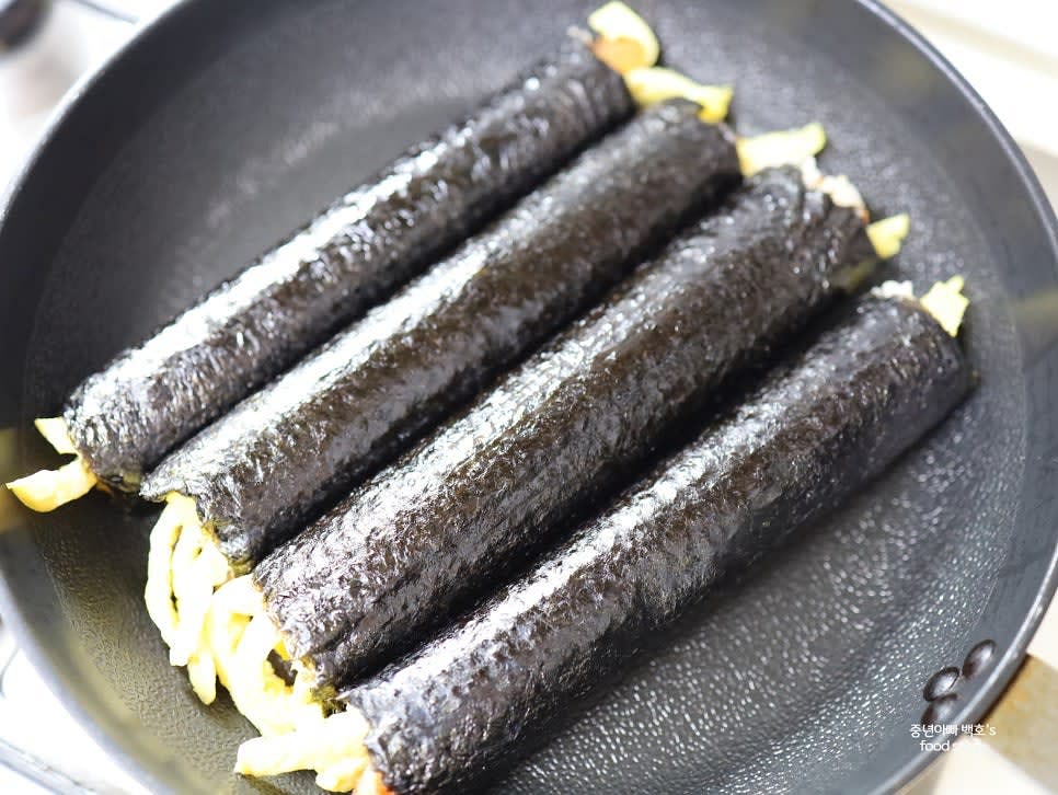 완성된 김밥은 팬에서 약불로 살짝 구워 고소한 맛을 더한 후, 일정한 크기로 잘라줍니다.
