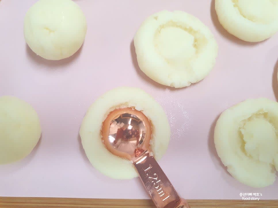 반죽을 경단처럼 동그랗게 만들고, 살짝 눌러 납작한 모양으로 만들어 주세요. 계량스푼 등으로 눌러 모양을 더해 주세요.