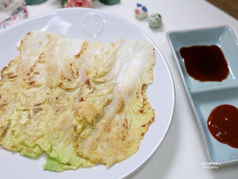 완성된 배추전을 접시에 담아 취향에 따라 양념간장이나 초고추장과 함께 제공합니다.