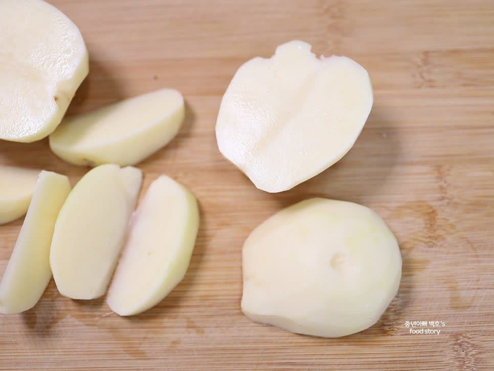 감자를 깨끗이 씻은 후 껍질을 벗기고 길게 반으로 자릅니다. V자 모양으로 잘라 웨지 형태로 준비합니다.
