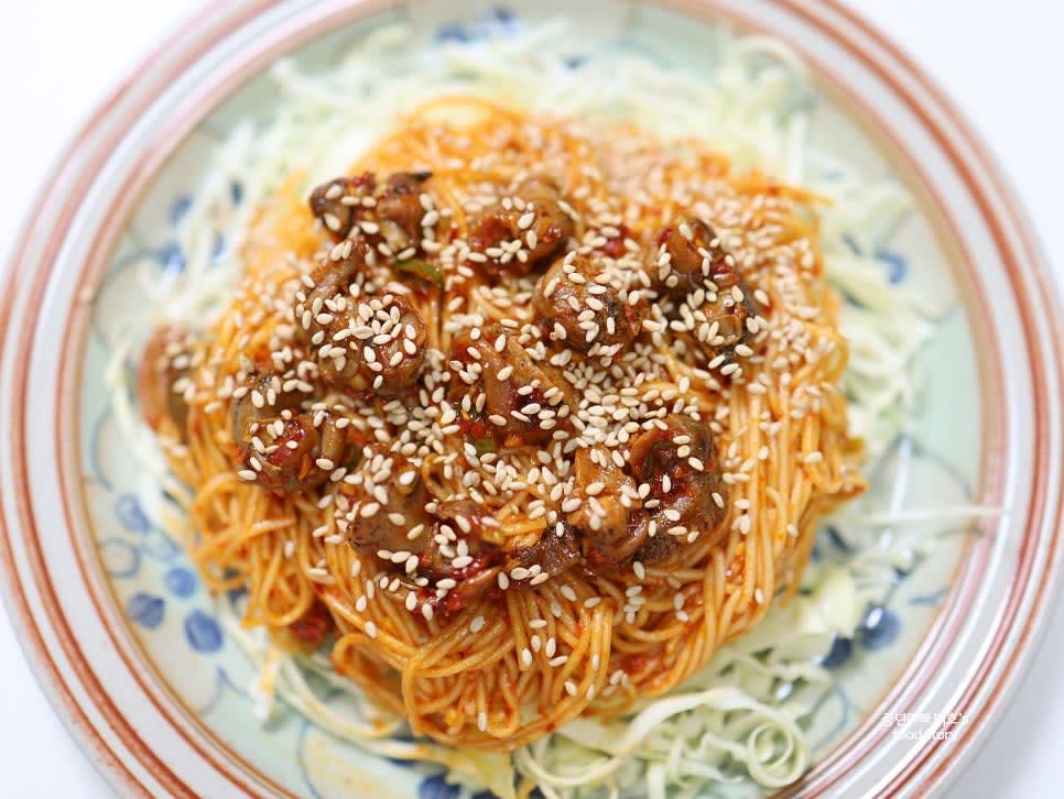 넓은 접시에 채 썬 양배추를 깔고, 불골뱅이볶음면을 그 위에 올립니다. 통깨를 솔솔 뿌리고 채 썬 대파를 올립니다.