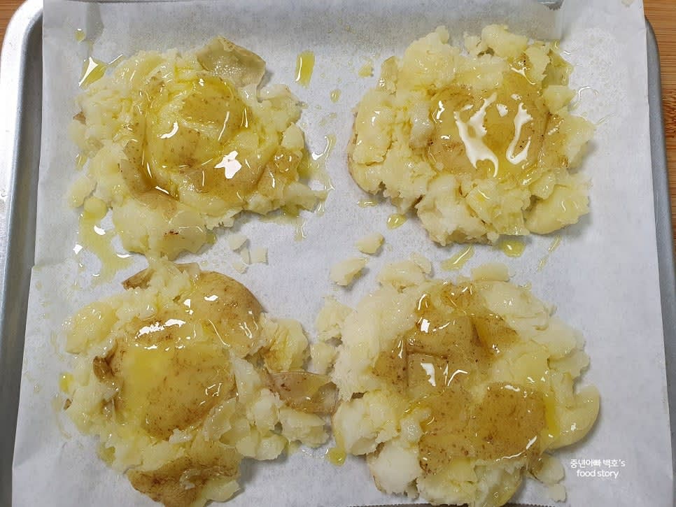 에어프라이어 망에 유산지를 깔고 납작한 감자를 서로 겹치지 않게 올립니다. 올리브오일을 뿌려줍니다.