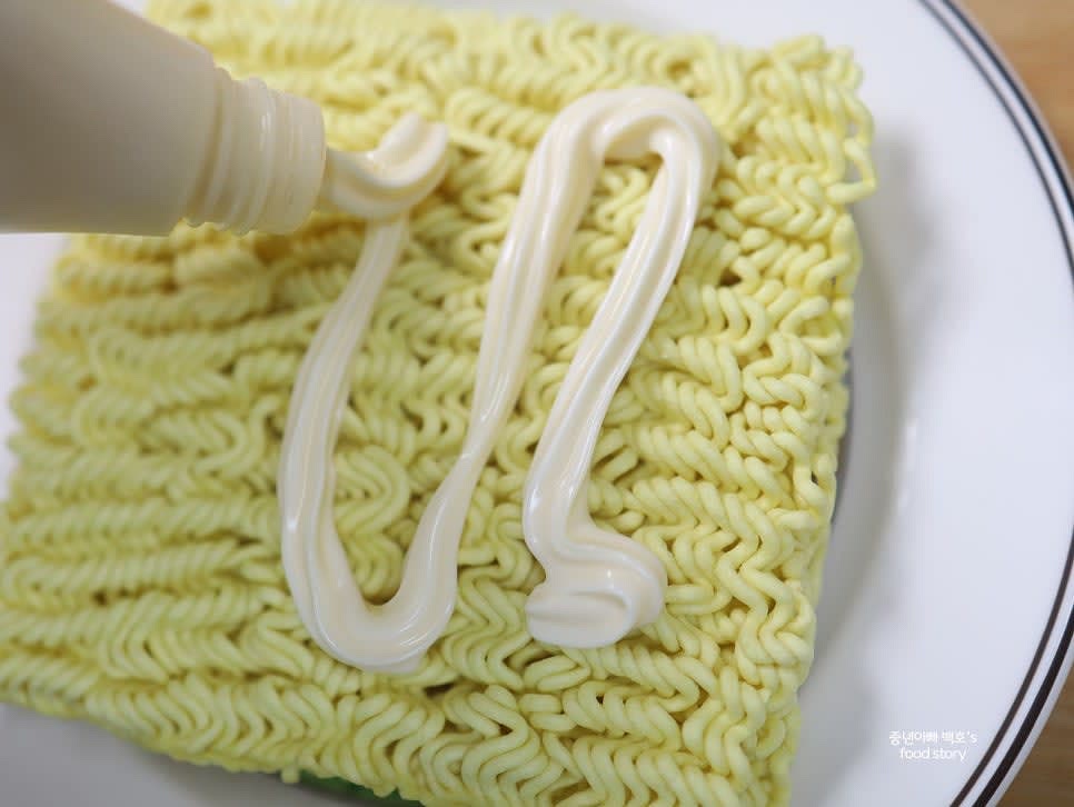 라면 위에 마요네즈를 적당량 뿌리고 수저로 고르게 펴줍니다. 가장자리는 약 1cm 정도 남겨 둡니다.