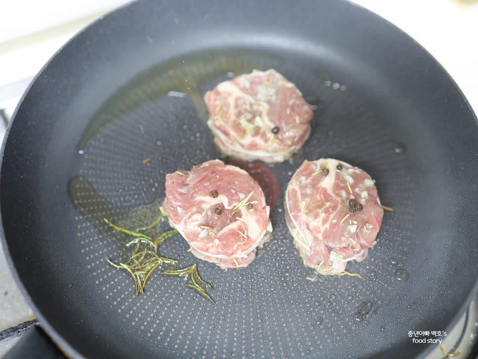 등심은 팬에 올리브오일을 두르고 뜨겁게 달군 후 로즈마리를 넣어 향을 더합니다. 각 면을 2~3분씩 뒤집어가며 굽습니다.