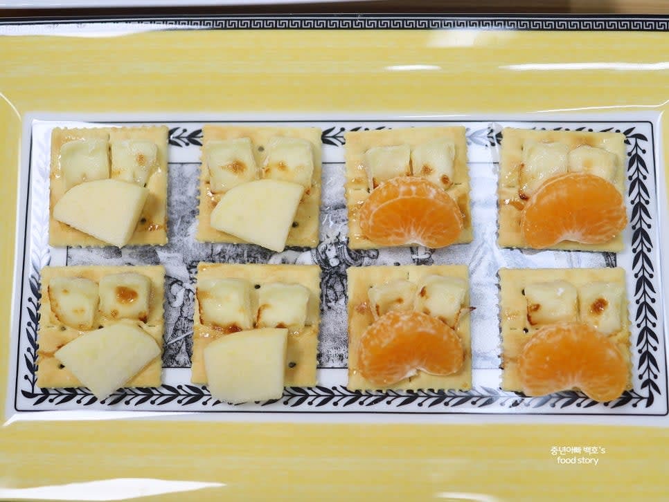 구워진 치즈 크래커 위에 슬라이스한 사과와 귤 조각을 올려주세요.