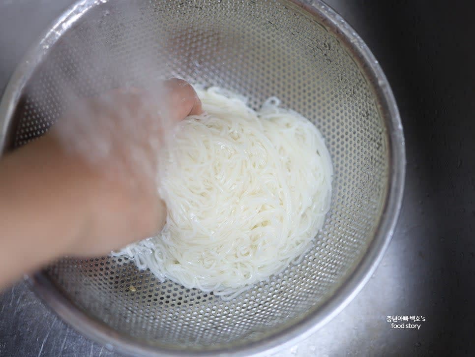 삶은 소면을 찬물에 헹구며 전분기를 제거한 뒤 물기를 짜고 참기름 1스푼으로 코팅합니다.