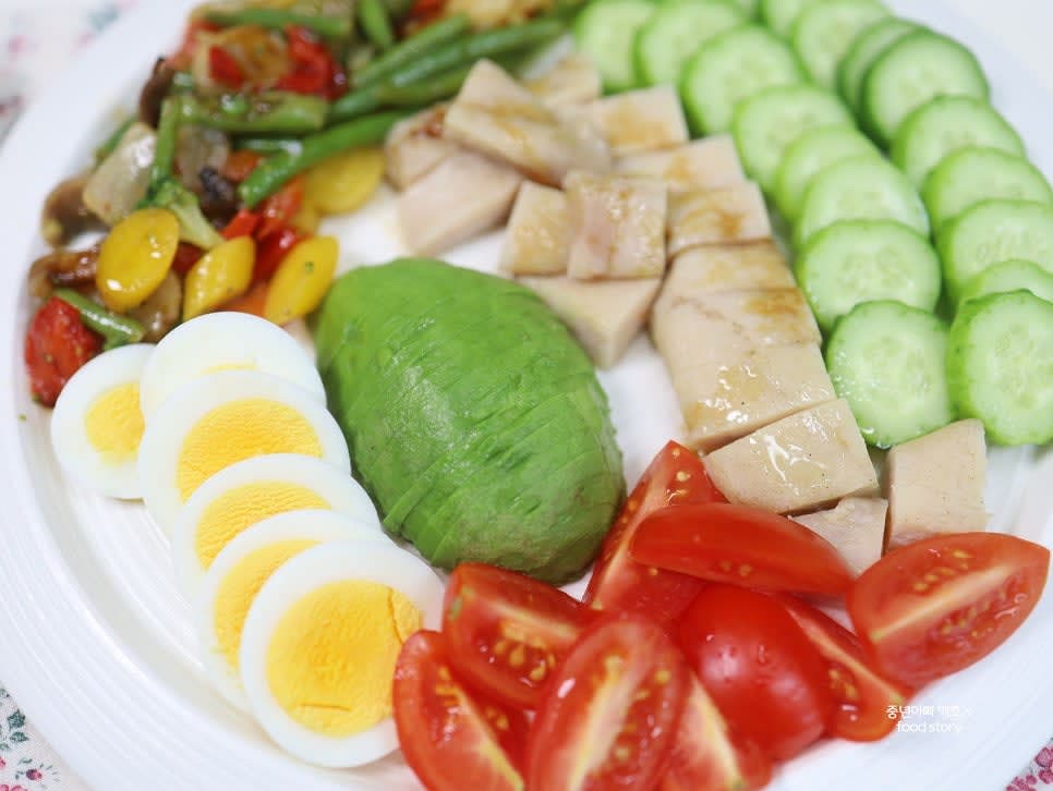 큰 접시에 준비한 아보카도, 닭가슴살, 삶은 달걀, 볶은 야채, 방울토마토, 오이를 보기 좋게 담습니다.