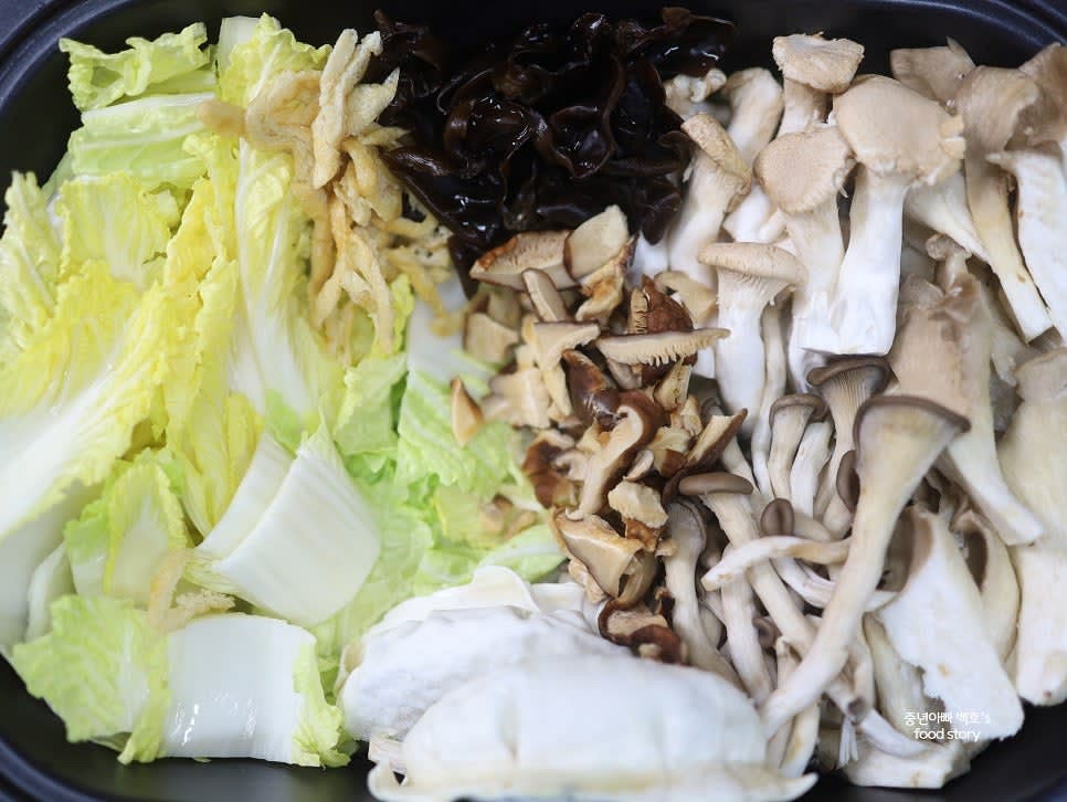 버섯 5종(느타리, 참타리, 표고, 목이버섯 등)과 슬라이스 유부, 만두를 배추 위에 올립니다.
