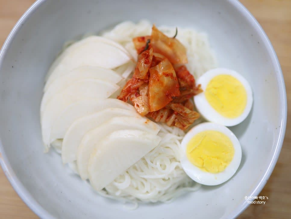 소면을 그릇에 동그랗게 말아 담고 무채, 김치, 삶은 계란을 고명으로 올립니다.