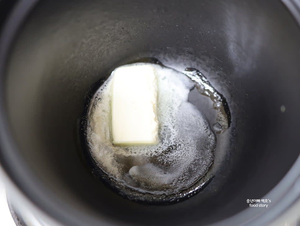 솥을 달군 후 버터 1/2스푼을 넣고 녹입니다. 불린 쌀을 넣고 2~3분간 고루 볶아줍니다.