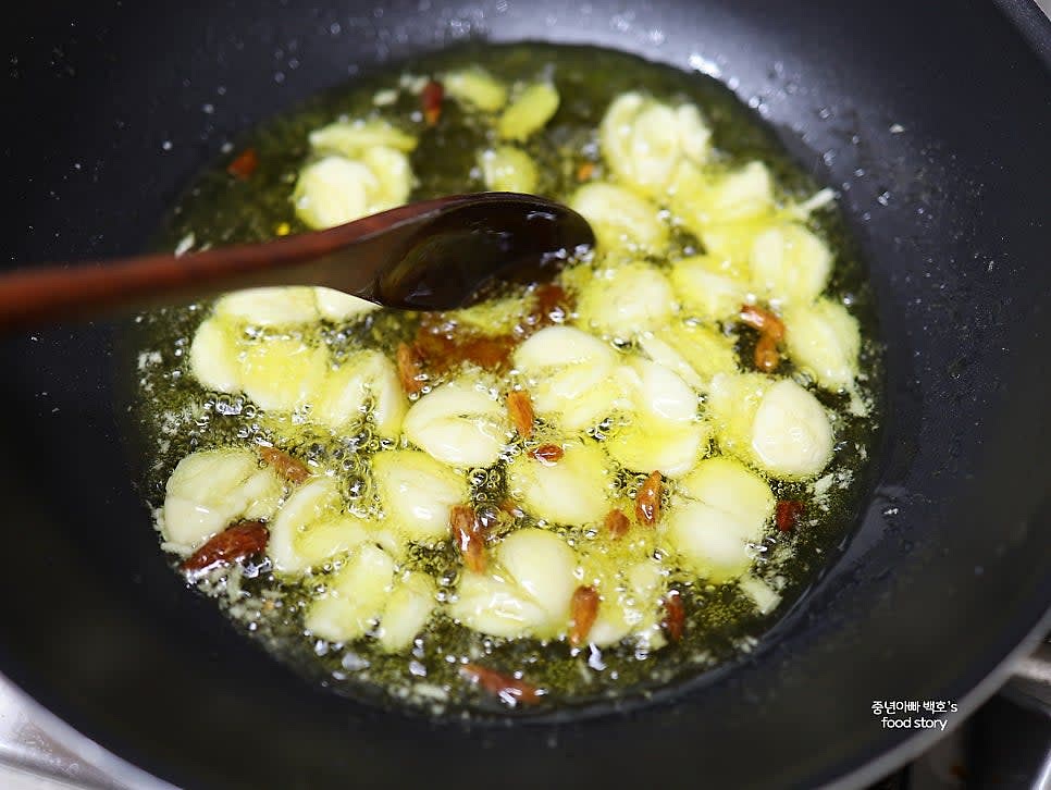 팬에 올리브오일 1컵을 붓고 중약불에서 으깬 마늘과 페페론치노를 넣어 향이 올라올 때까지 볶습니다.