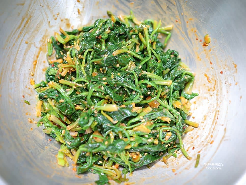 완성된 고추장 시금치무침을 접시에 담아 통깨를 추가로 뿌려 마무리합니다.