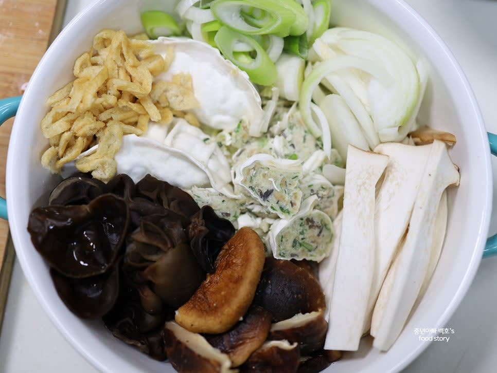 냄비에 배추를 깔고 준비된 버섯, 야채, 유부, 썰어 놓은 만두를 차례대로 올립니다.