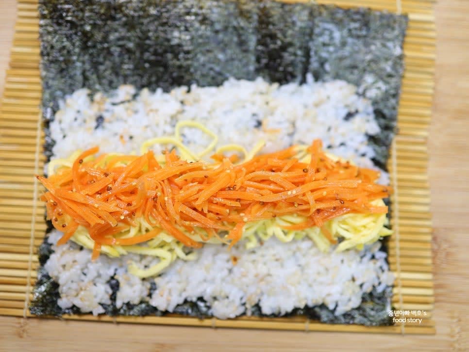 밥 위에 계란지단, 당근라페, 단무지를 중앙에 놓습니다.