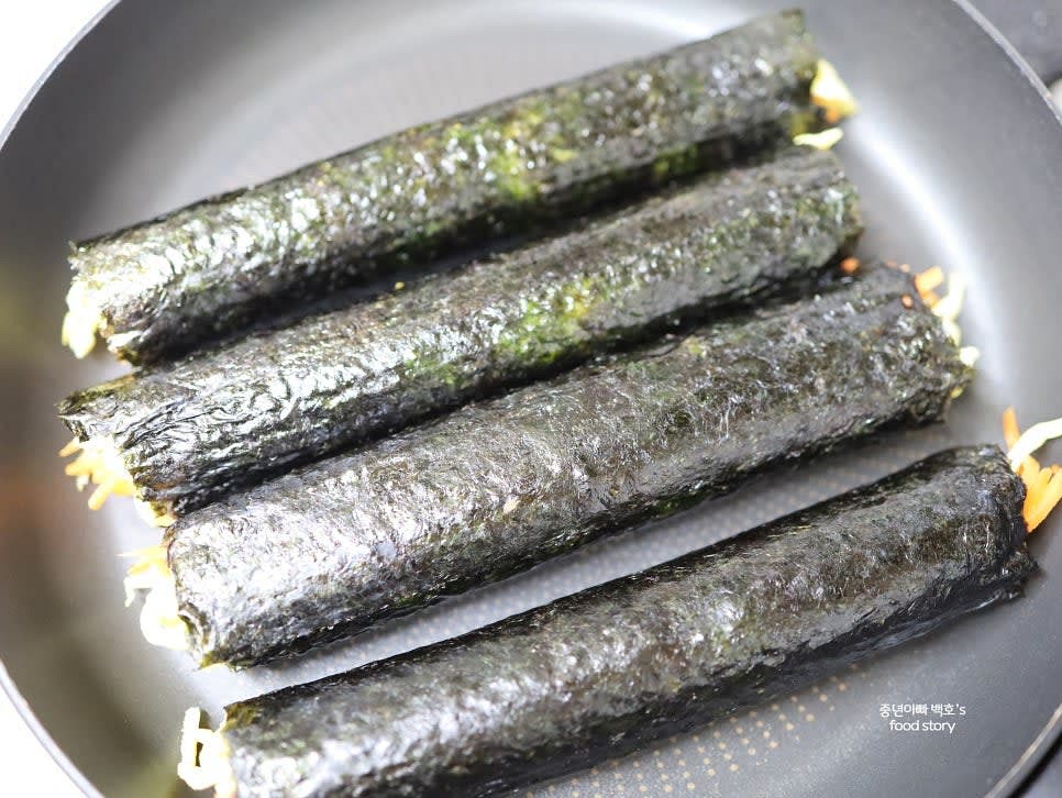 팬에 약불로 김밥 겉면을 살짝 굴리듯 구워줍니다. 참기름을 발라주면 더 고소한 맛을 낼 수 있습니다.