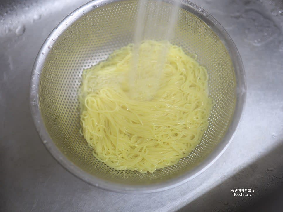 소면이 적당히 익었는지 확인한 후 불을 끄고 찬물에 헹구어 전분기를 제거합니다. 두 손으로 물기를 짠 후 채반에 밭쳐둡니다.