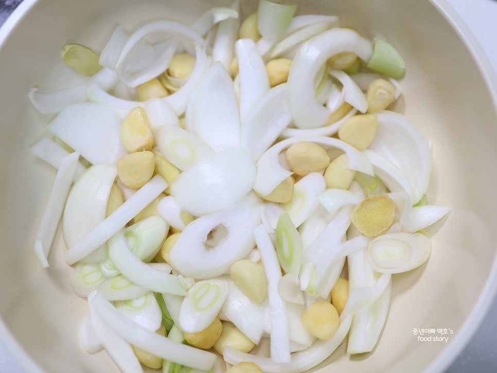냄비나 웍에 양파 채썬 것, 대파 흰 부분 어슷썰기, 통마늘, 생강을 바닥에 깔아줍니다.