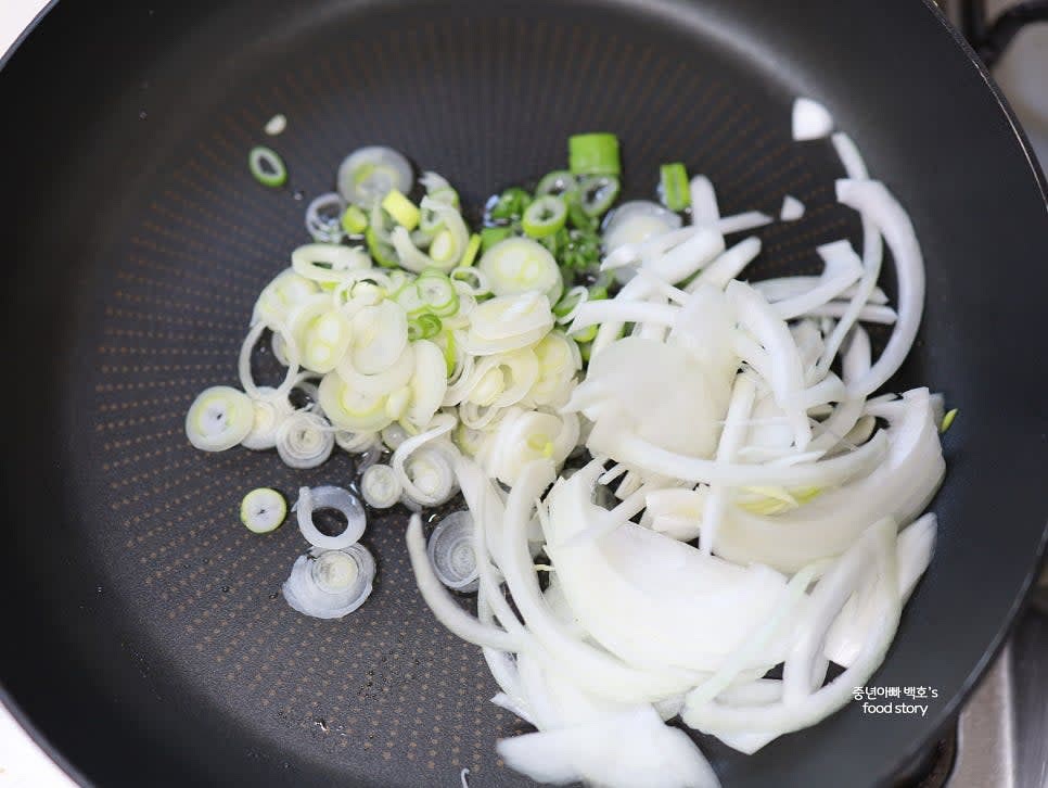 팬에 식용유 3스푼을 두르고 대파와 양파를 넣어 중약불에서 양파가 투명해질 때까지 볶습니다.