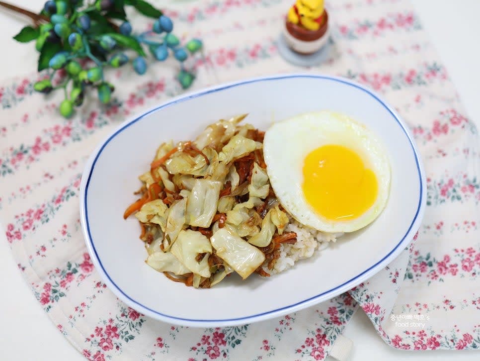 그릇에 밥을 담고 양배추볶음을 올린 뒤, 한쪽에 계란 프라이를 올려 완성합니다.