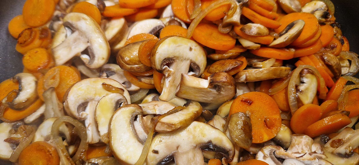 Füge die Champignons hinzu und brate sie, bis sie weich sind und etwas Flüssigkeit abgegeben haben.