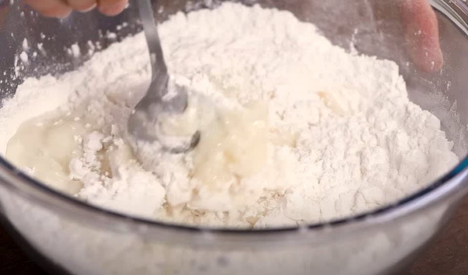 Pour the warm liquid into the mixer bowl with the dry ingredients. Use a spatula to start mixing to minimize the mess. Once the liquid is incorporated, use an electric mixer with a flat beater blade on low speed for about 5 minutes to cool down the dough.