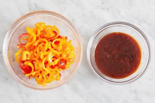 Cut off and discard the stems of the peppers; remove the cores. Halve lengthwise, then thinly slice crosswise. Cut the ends off of the peas. In a bowl, whisk together the ketchup, honey, soy sauce, sesame oil, 2 tablespoons of warm water, and as much of the sambal oelek as you’d like.