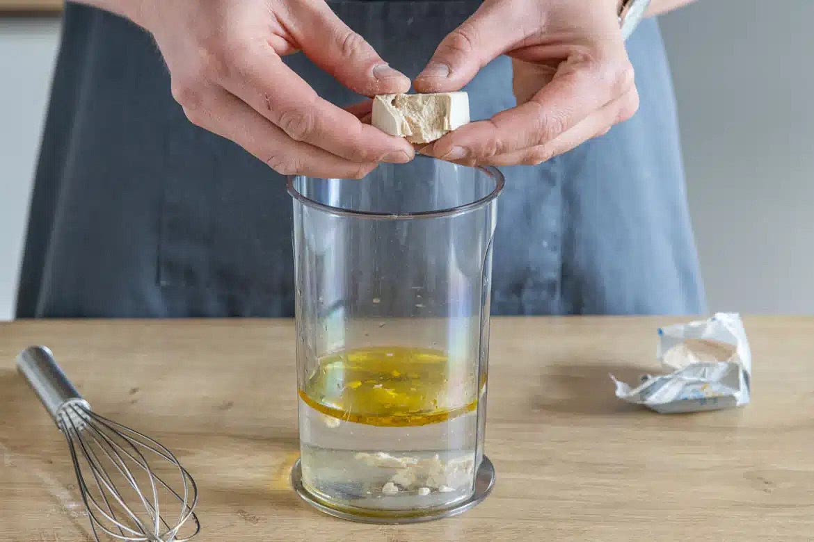 Olivenöl, Wasser und Zucker in ein Gefäß geben. Hefe hineinbröseln, alles verrühren und für 10 Minuten stehen lassen.